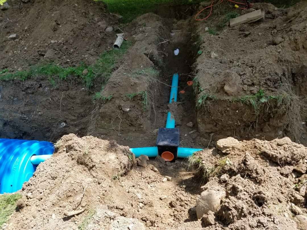 Sewer line and tank connection in an open trench
